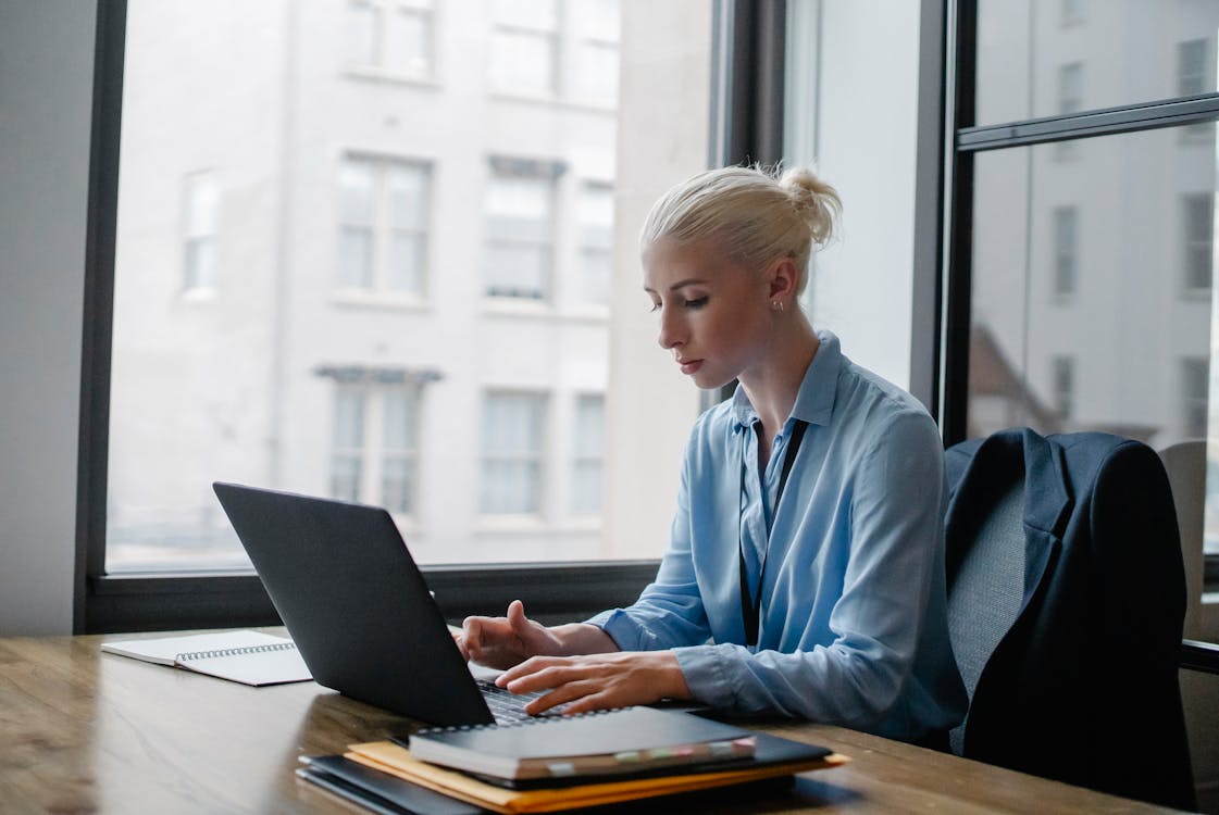 A focused woman typing on a laptop in a professional workspace, representing authentic human content creation as an alternative to AI-generated slop